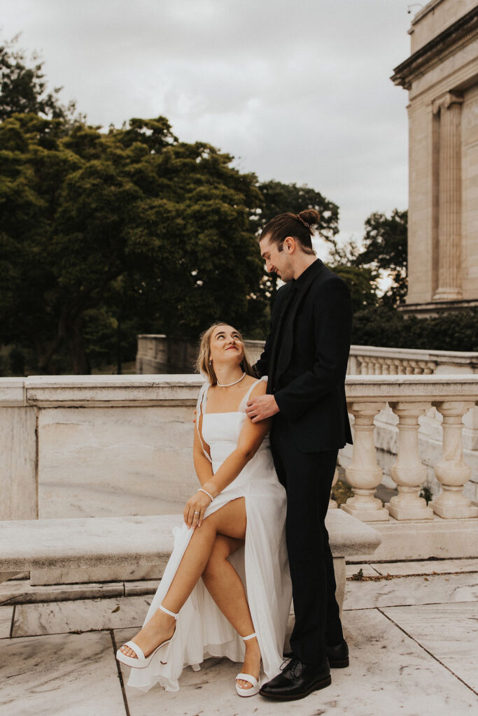 couple pose together on a marble bench