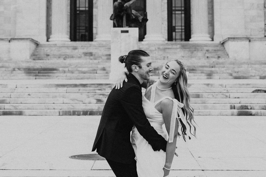 couple embrace while laughing during engagement photos