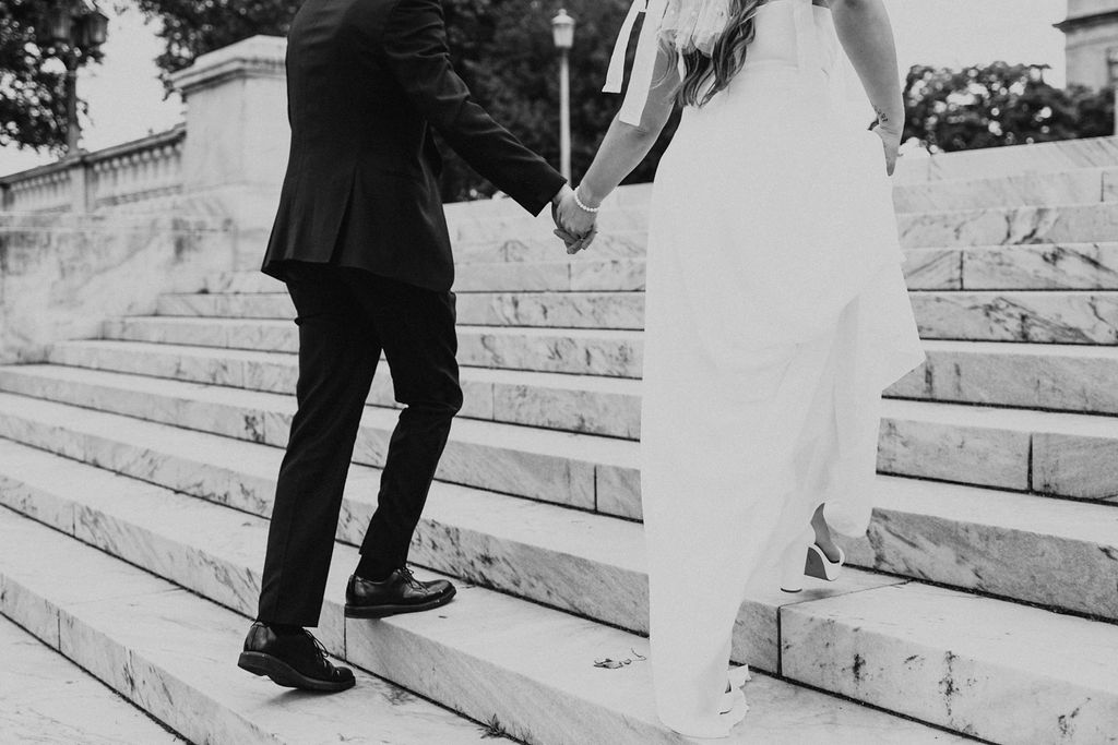 couple holds hands while walking up steps