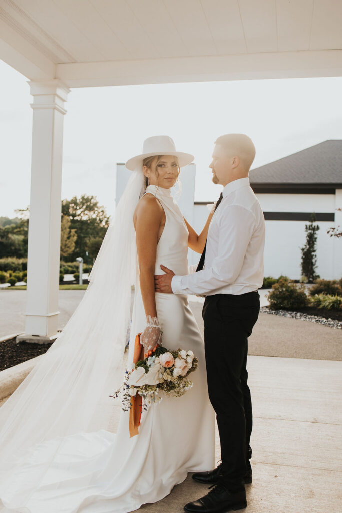 couple poses in front of Westbrook Country club during sunset