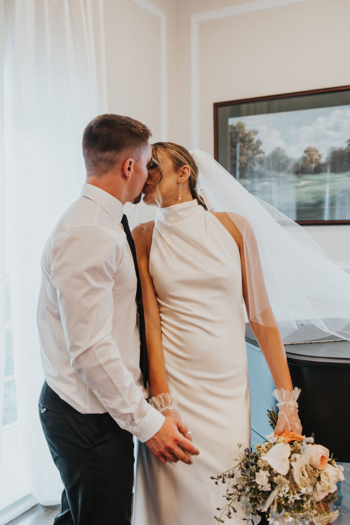 couple kiss while posing with piano