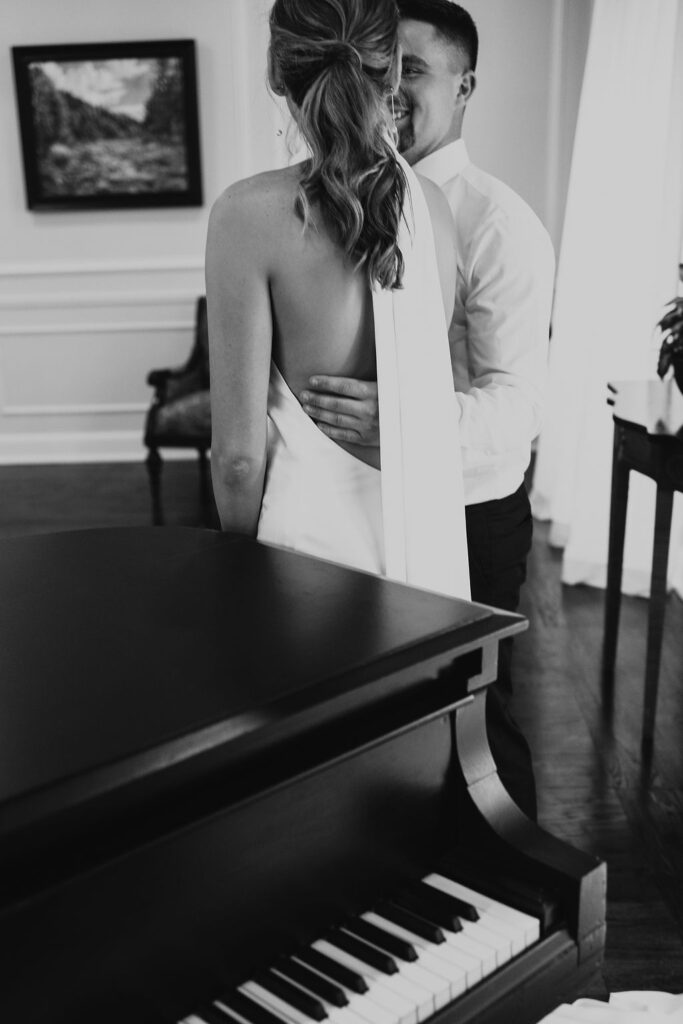 couple pose while posing with piano