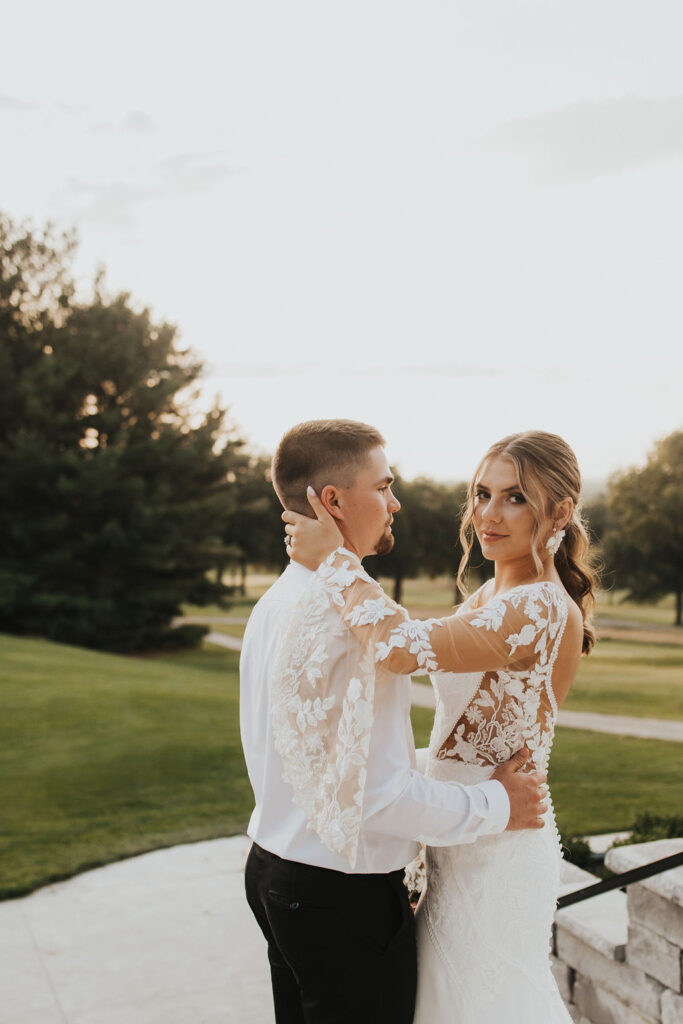 couple poses on steps overlooking the golf course