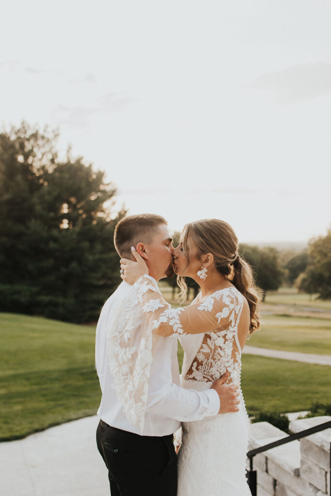 couple kisses on steps overlooking the golf course