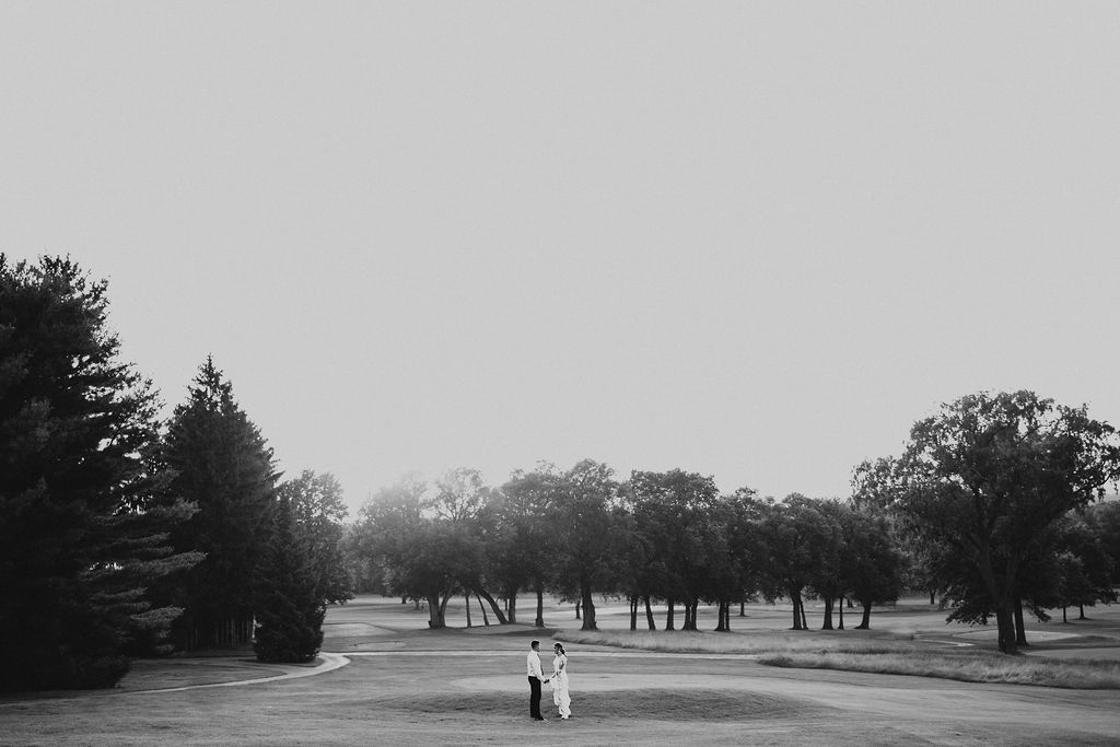 couple holds hands on golf course during sunset